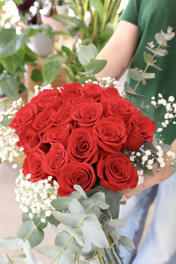 Ramo de veinte rosas de color rojo sostenido por nuestra florista Júlia