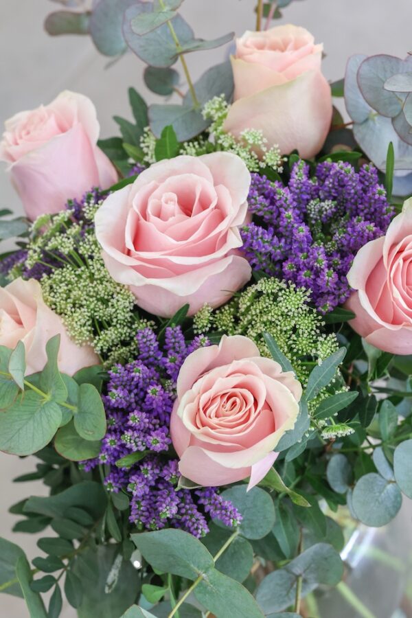 Fotografía de detalle de un ramo de flores que contiene seis rosas de color rosado.
