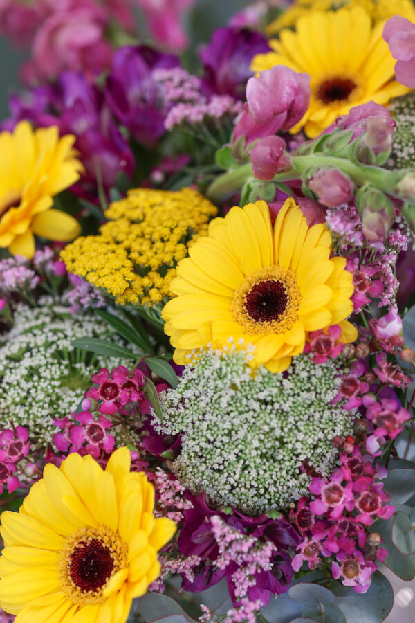 ramo de gerberas amarillas combinado con flor silvesre de tonos rosados y lilas con mucho volumen
