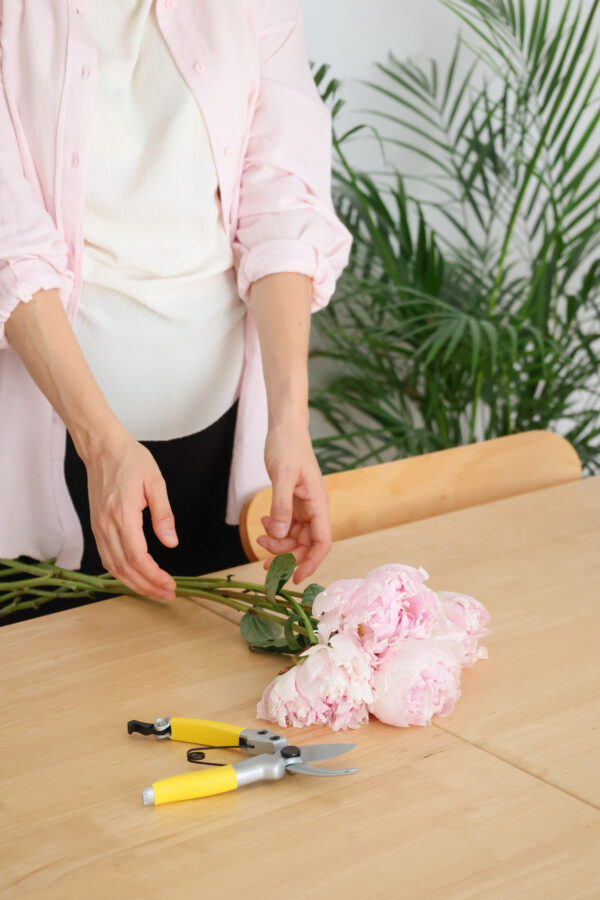 Mujer preparando un ramo de peonías de color rosado