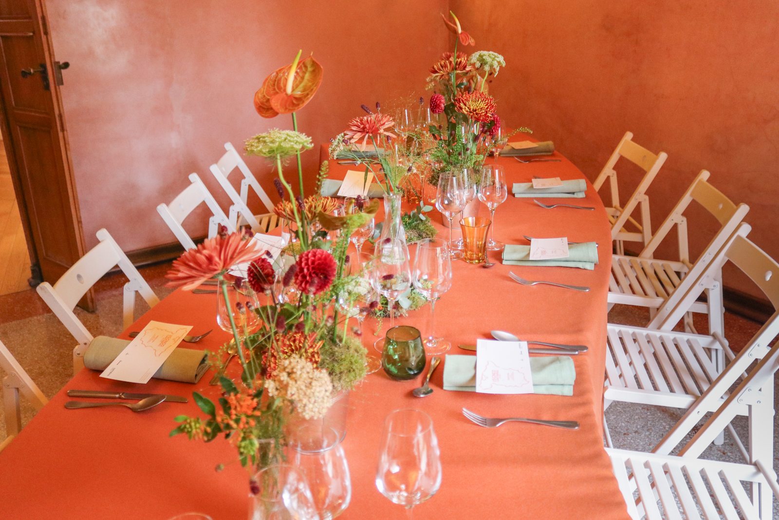 Mesa preparada para la cena en Casa Vicens con centros florales de BonBee y mantel naranja